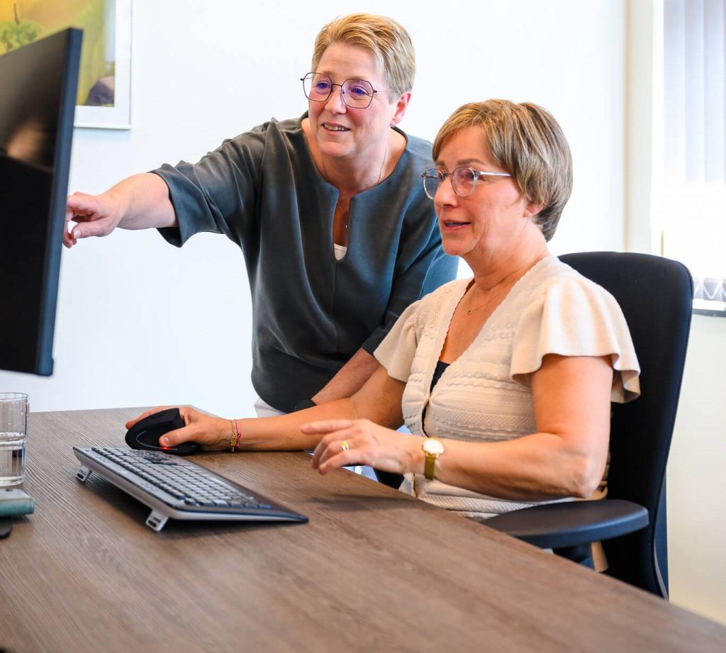 Twee vrouwen werken samen achter computer.